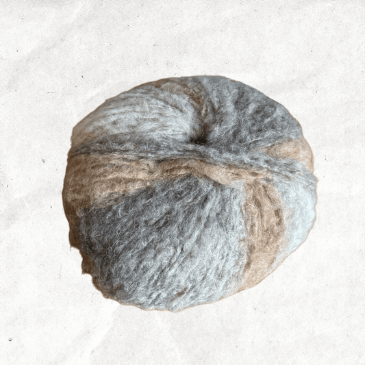 A fluffy ball of yarn with beige and grey tones.