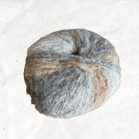 A fluffy ball of yarn with beige and grey tones.