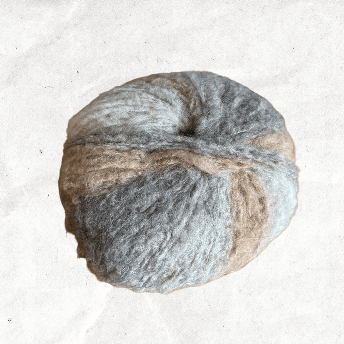 A fluffy ball of yarn with beige and grey tones.