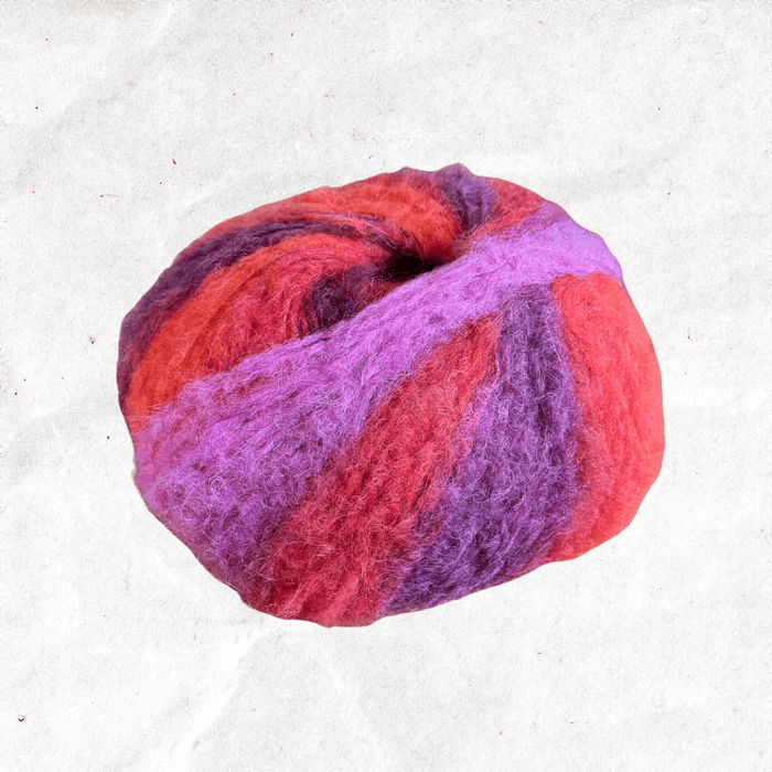 A fluffy ball of yarn with pink, purple, and red tones.