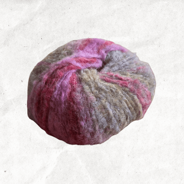 A fluffy ball of yarn with beige, grey, and pink tones.