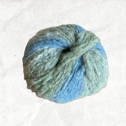 A fluffy ball of yarn with baby blue and light green tones.