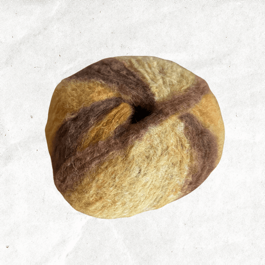 A fluffy ball of yarn with yellow and golden brown tones.