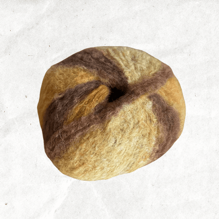 A fluffy ball of yarn with yellow and golden brown tones.
