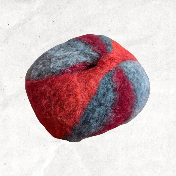A fluffy ball of yarn with red, orange, and blue-grey tones.